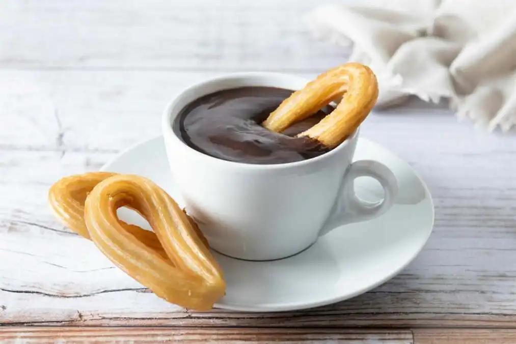 Saboreando los sabores de la cocina española 12 Desayuno tradicional español de churros con chocolate caliente mesa de madera 2 escala 1
