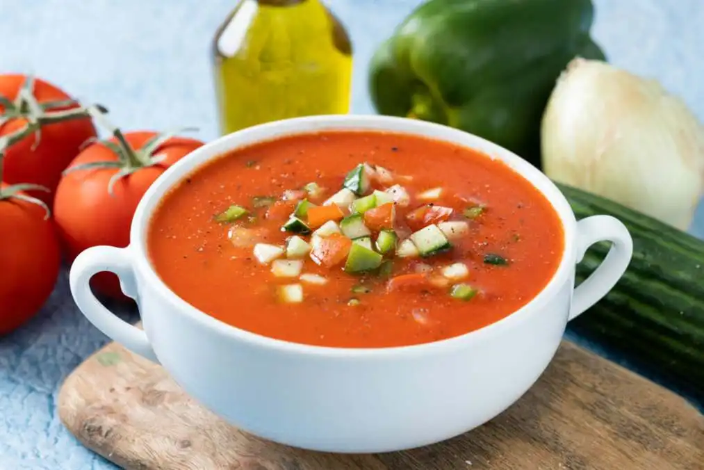 Saboreando los sabores de la cocina española 10 Cuenco de sopa tradicional española de gazpacho sobre fondo azul escala 1